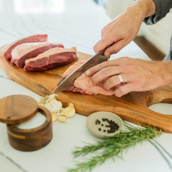 Forged 8" Chef's Knife with Sierra Handle, shown slicing a cut of beef